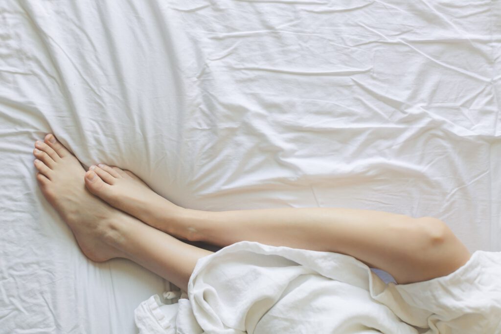 Beine auf einem weißen Bettlaken